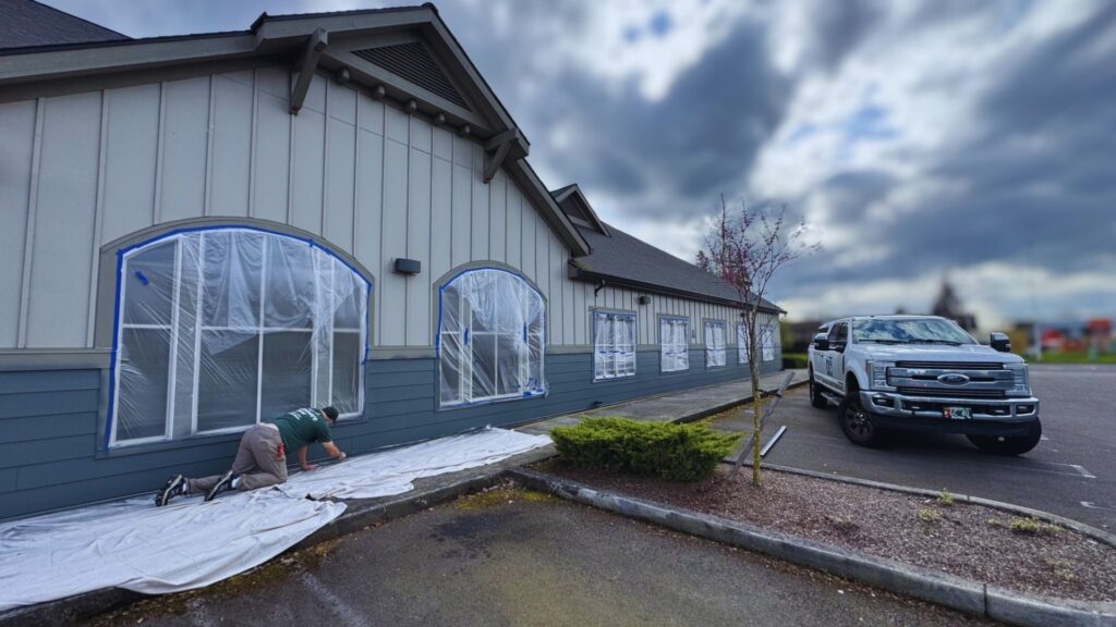 mid-commercial painting job showing someone actively painting the siding of the commercial building