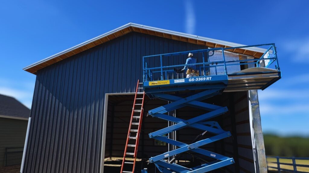 pole barn nearly completed with DCI work on a raised scissor life working on the gutter system