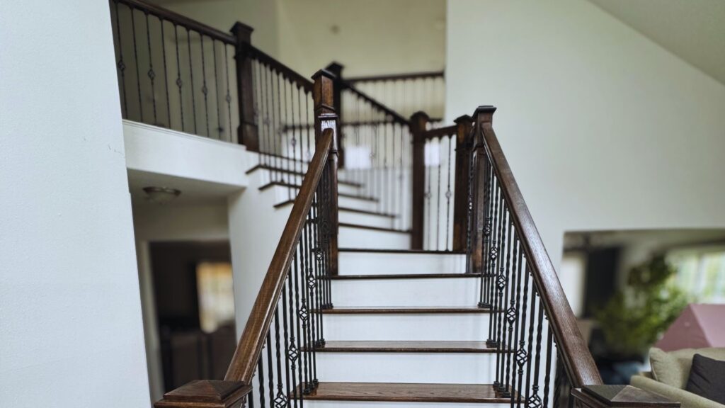 front view facing a newly installed oak staircase with newel craftsmen posts and wrought iron spindle railing supports